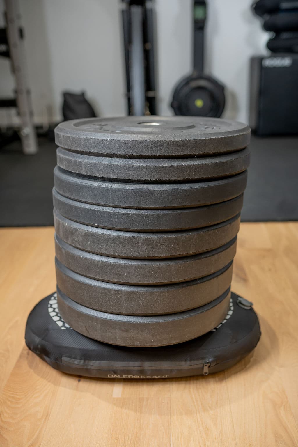A tall stack of iron weight plates resting on a BALEROboard